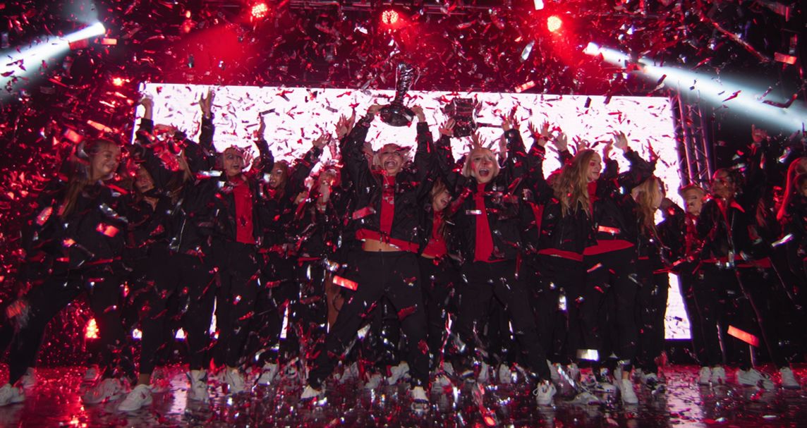 Group of dancers lifting trophy and celebrating with confetti falling around them
