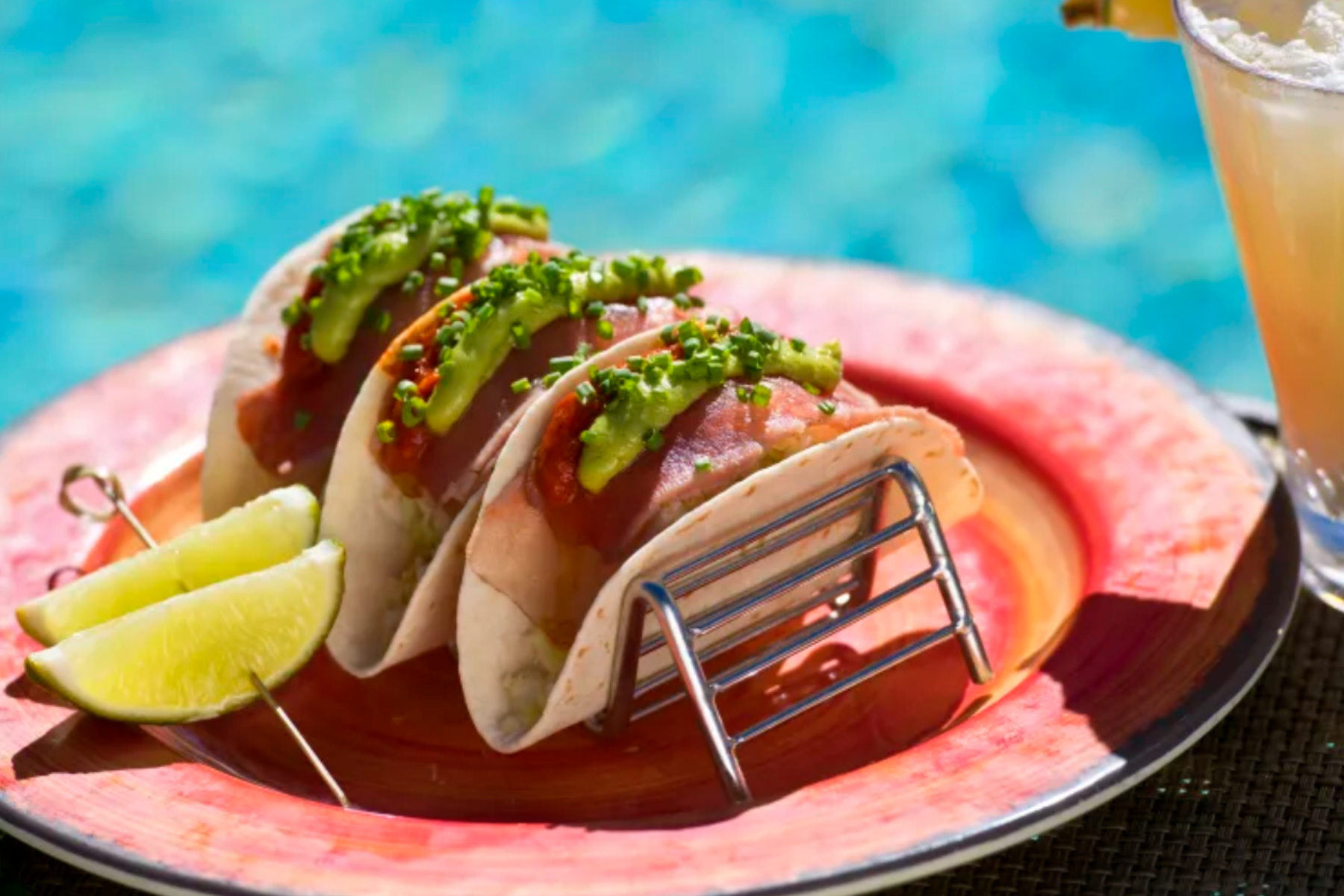 Three tacos with two lime slices on a skewer