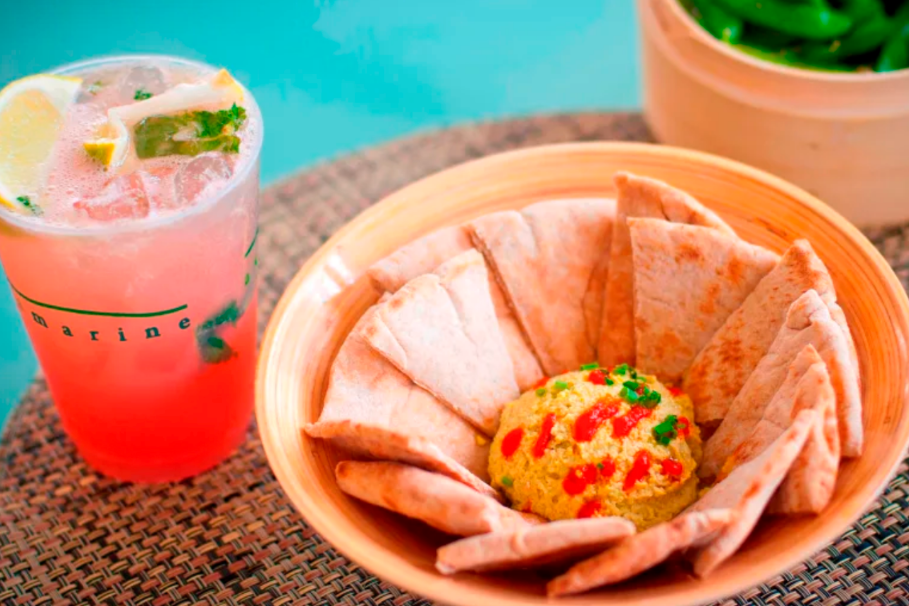 Pita bread triangles with dip and pink beverage with lemons